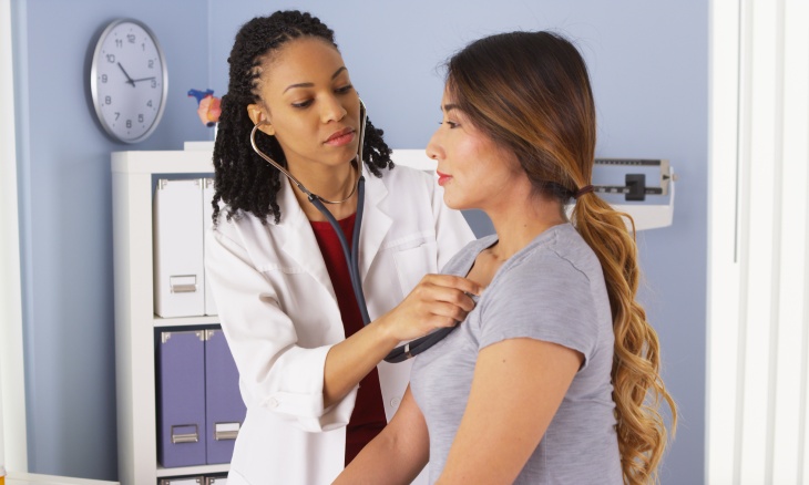 A doctor checks her patient's heart.