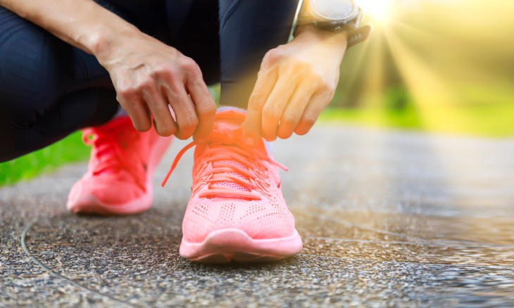 Woman lacing up her pink sneakers to go walking.
