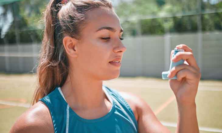 Woman uses an inhaler to combat asthma due to allergies