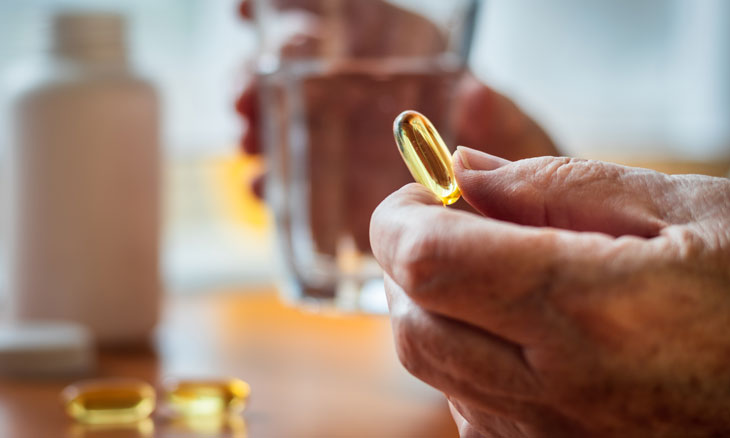 Person holding a vitamin supplement.