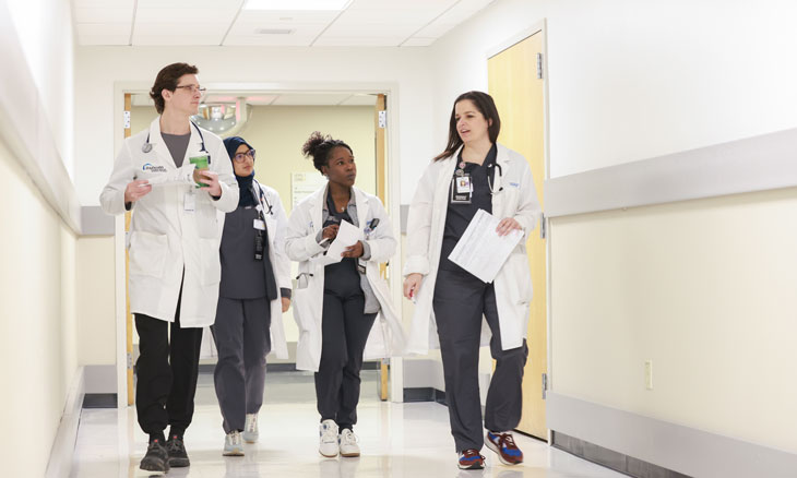 Internal medicine residents conversing in a hospital hall way.