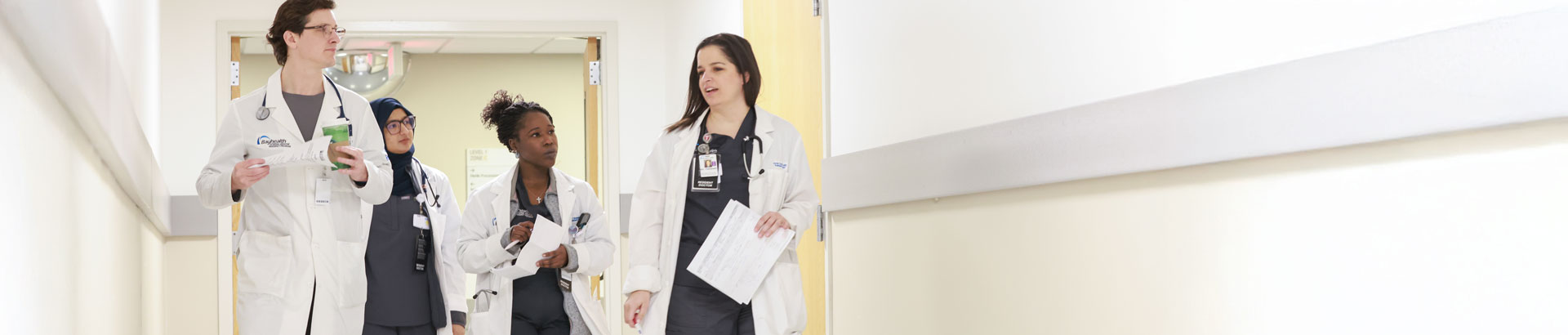 Internal medicine residents conversing in a hospital hall way.