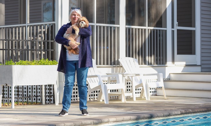Dawn Ellis stands on her backyard patio holding her dog.